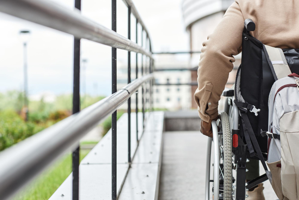 Крупний план руки людини на інвалідному візку, який котиться вниз по рампі, ілюструючи досягнення у сфері доступності інфраструктури